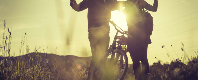 sunset couple standing by a bike